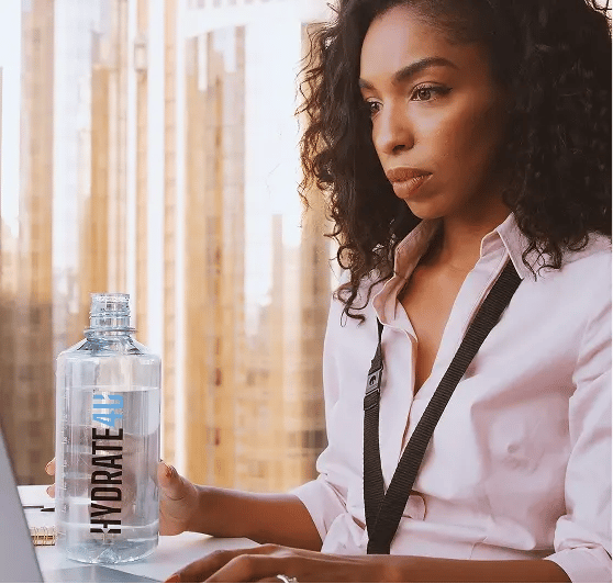 Hydrate4U woman drinking water by the desk